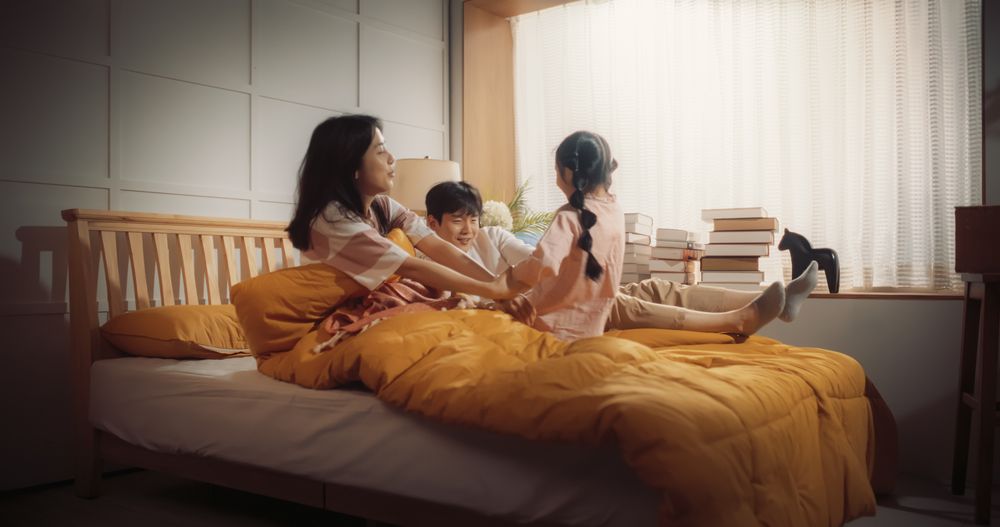 Happy Korean Family in the Morning: Active and Playful Child Running to her Parents' Bedroom to Wake Them Up.