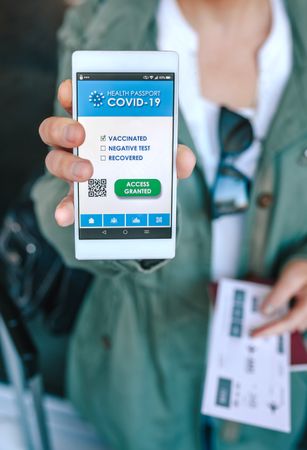Woman showing covid passport on the smartphone at an airport con