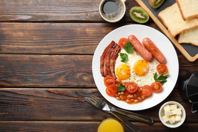 Top view of fried eggs, breakfast with kiwi, coffee and juice on table, copy space