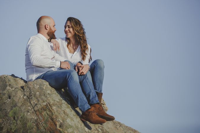 Happy couple sitting at mountain cliff