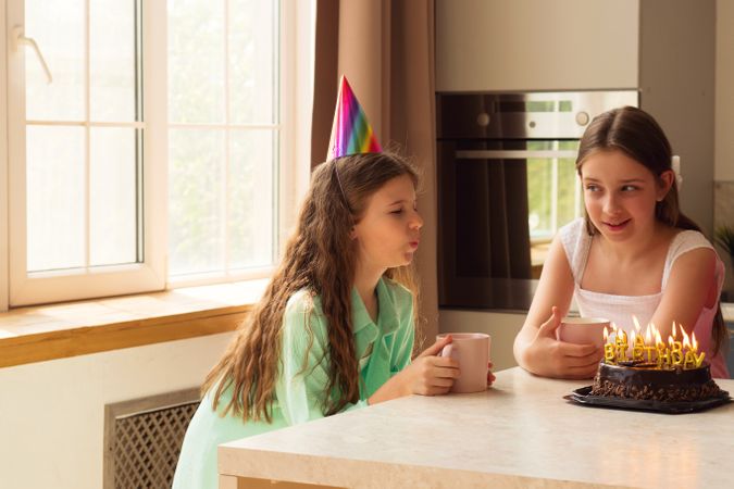 Girls birthday celebration, one blowing out candles on cake.