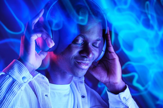 Positive Black man enjoying music in headphones
