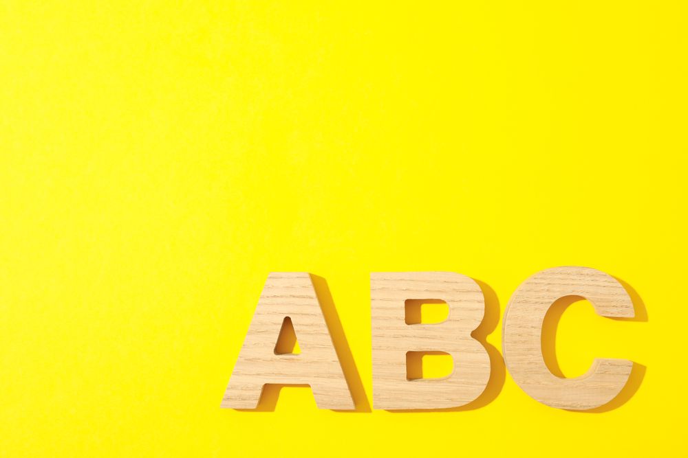 Wooden letters of English alphabet on color background, space for text