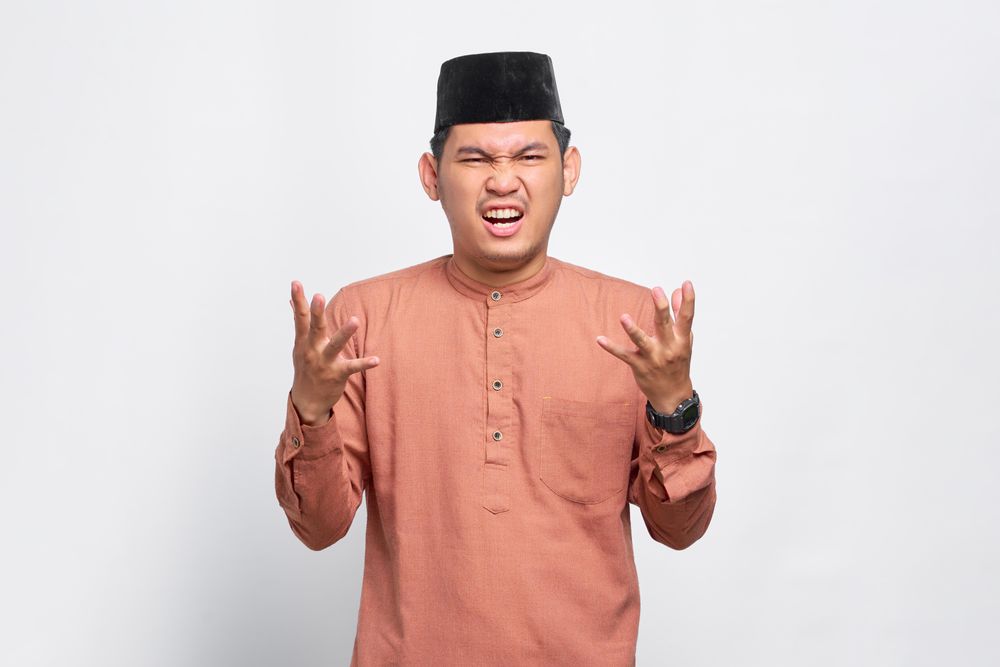 Iritated Muslim man in kufi head wear with his hands up