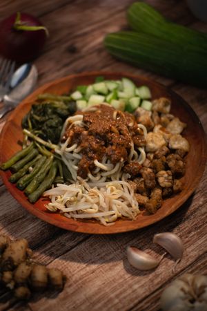 A plate of food with noodles and vegetables on a wooden table.