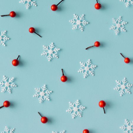 Christmas pattern made of snowflakes and red berries on blue background