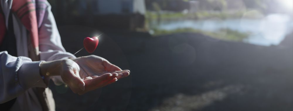Caring gesture of a woman with a shining red heart