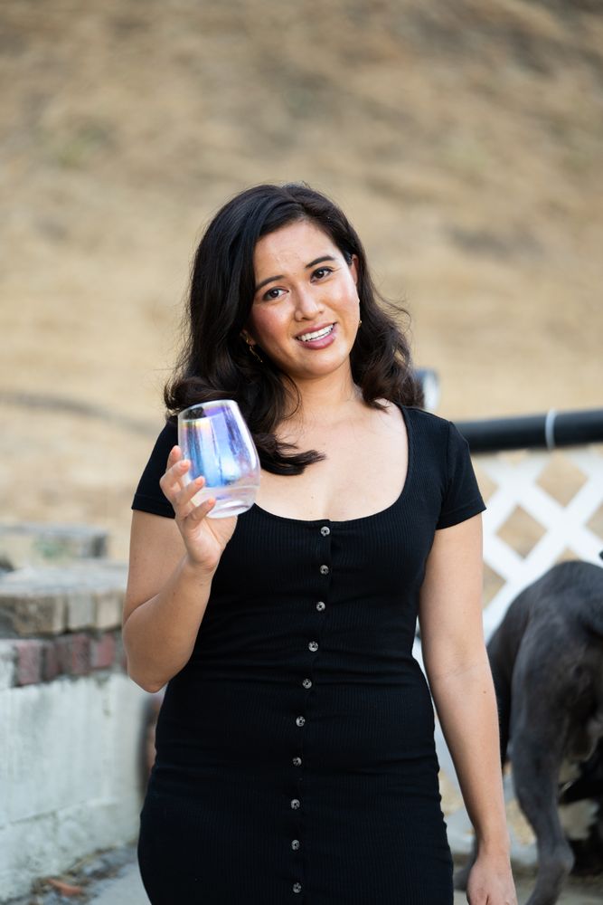 Portrait of woman holding glass of wine smiling and looking at camera outside