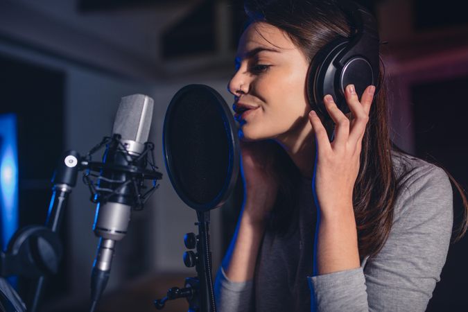 Close up of female vocal artist singing in a recording studio
