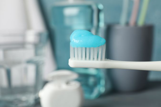 Toothbrush with toothpaste on background with dental care tools, close up