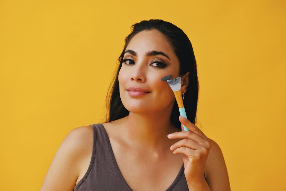 Latina woman applying clay mask with brush
