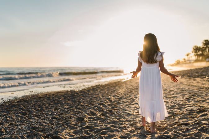 Excited girl running along beach in daylight