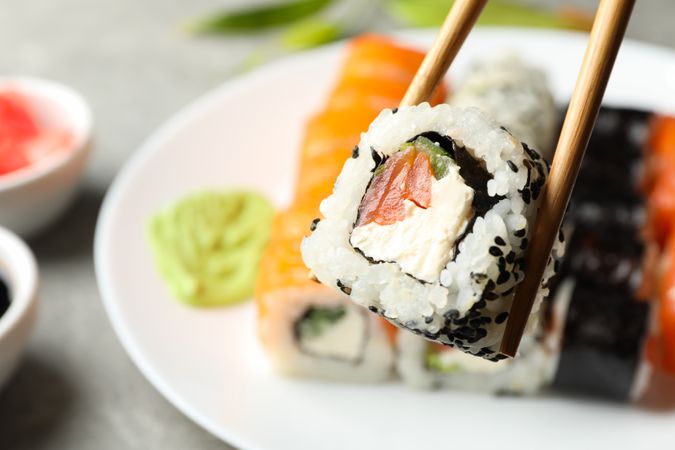 Chopsticks with delicious sushi roll, close up. Japanese food