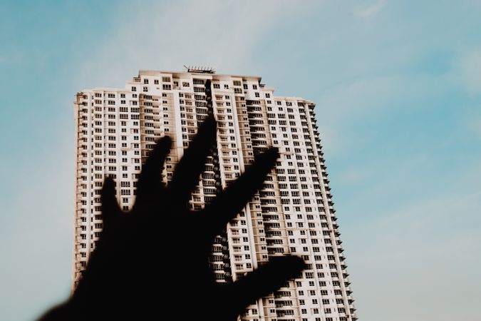 Hand reaching to tall building