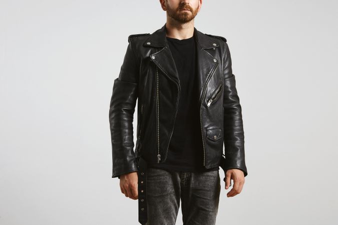Man in dark leather biker jacket on light background