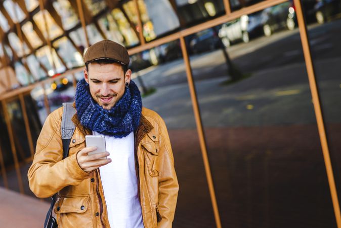 Stylish guy using smartphone outside modern building