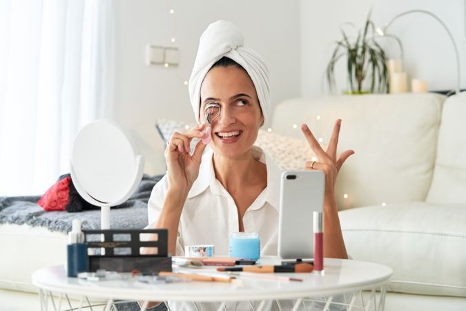 Happy woman applying eyelash curler