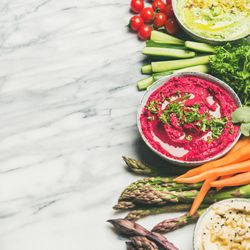 Fresh colorful vegetables and dips with hummus, avocados, asparagus, square crop with copy space