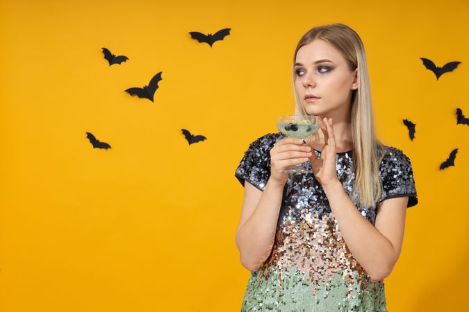A woman at a party in the style of Halloween with a cocktail in her hands