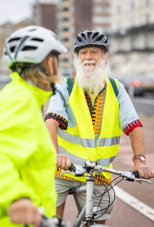 Happy older people with bikes stopped and talking, vertical