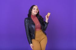 Woman showing a credit card on purple background. Shopping concept.