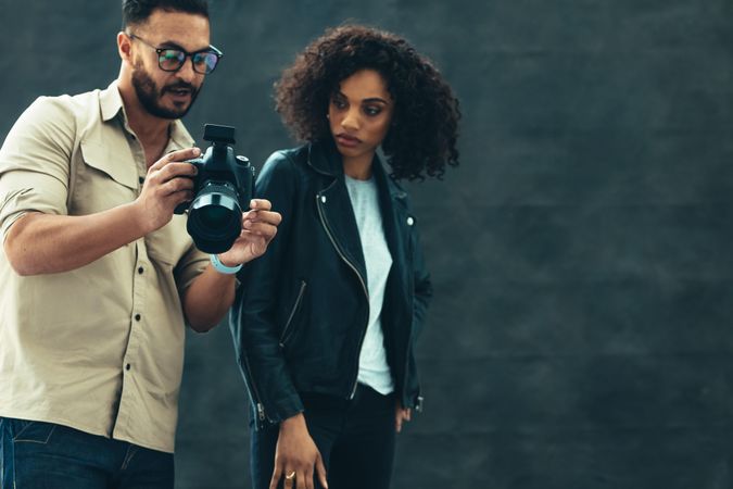 Studio shot of a photographer showing his camera to a model