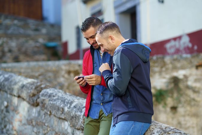 Male couple smiling at something over a phone