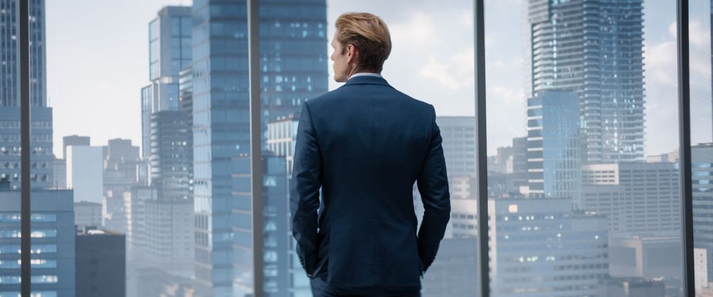 Thoughtful Young Businessman in a Perfect Tailored Suit Standing in His Modern Office