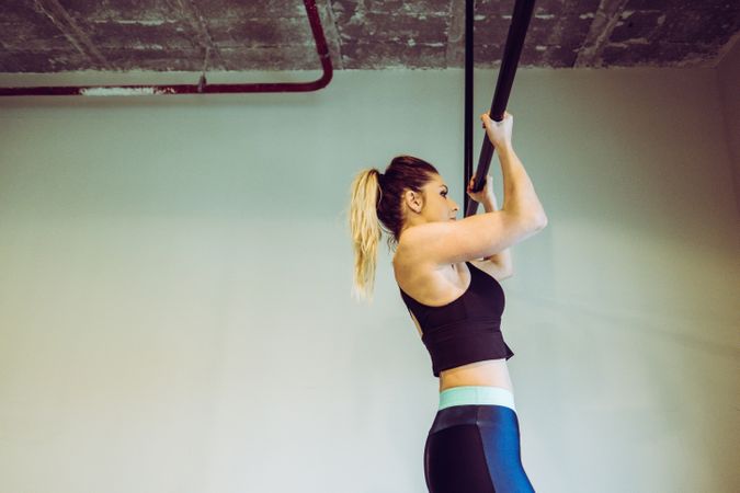 Young woman doing pull ups in gym