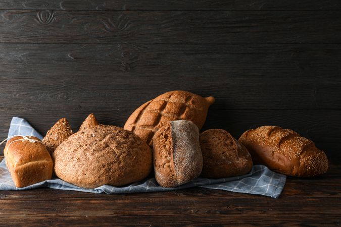 Bakery products on kitchen towel on wooden table against wood background, space for text