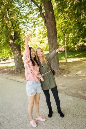 Cheerful multiethnic women greeting friend in park
