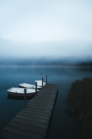Three dinghies near dock on foggy lake