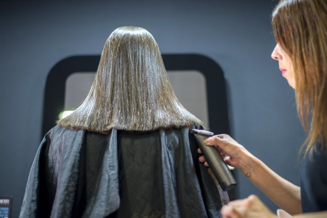 Hair stylist trimming ends of female customer