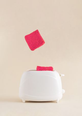 Pink toast popping out of toaster on a soft bright beige background