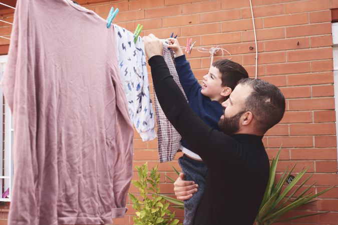 Father and son hanging clothes on rope