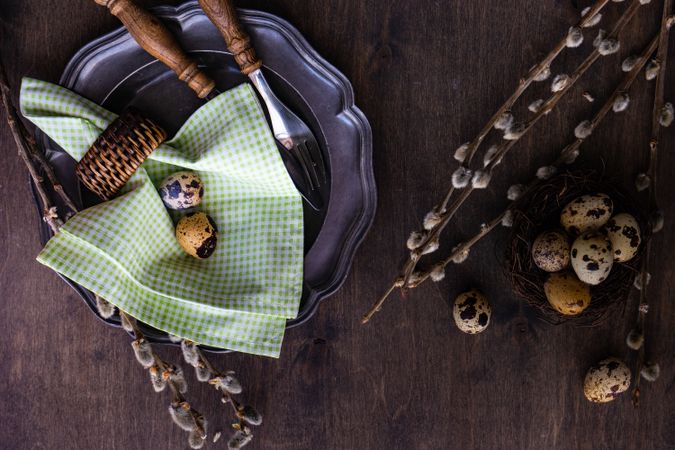 Top view of Easter table setting with quail eggs and pussy willow and checkered green napkin