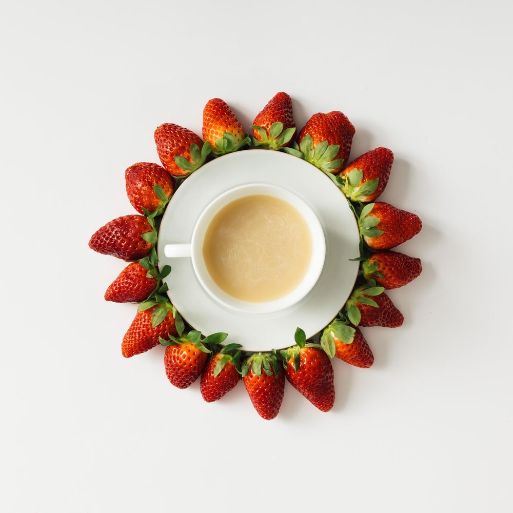 Coffee and saucer surrounded with strawberries
