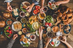 Group of people at Turkish breakfast with eggs, breads, vegetables, tea and honey