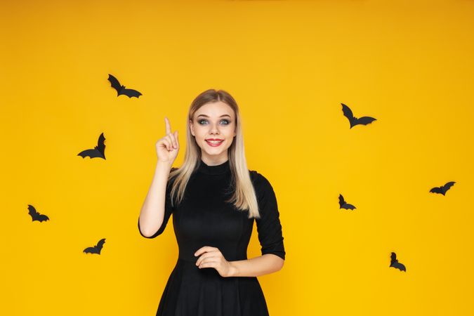 Concept of Halloween, young woman on yellow background