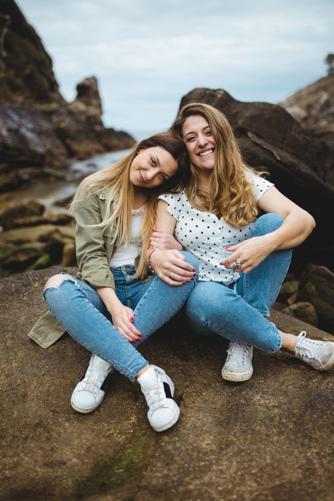 Young sisters sitting on stone on spring day