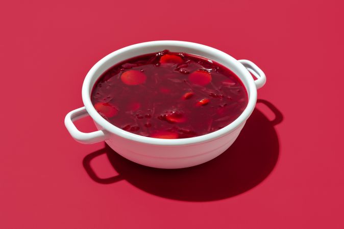 Red beet soup bowl on a red background