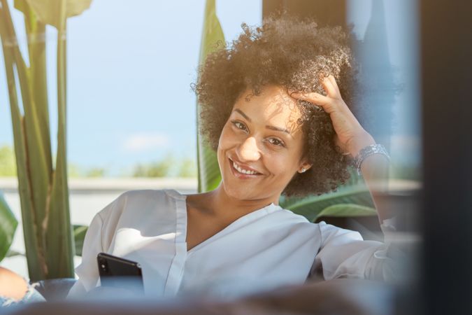 Smiling Hispanic woman with smartphone on terrace