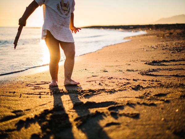 Cute little girl playing with sand at beach