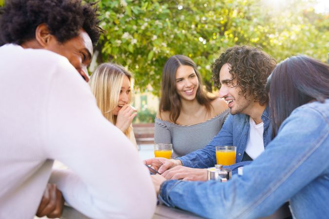 Friends laughing over coffee and juice outside