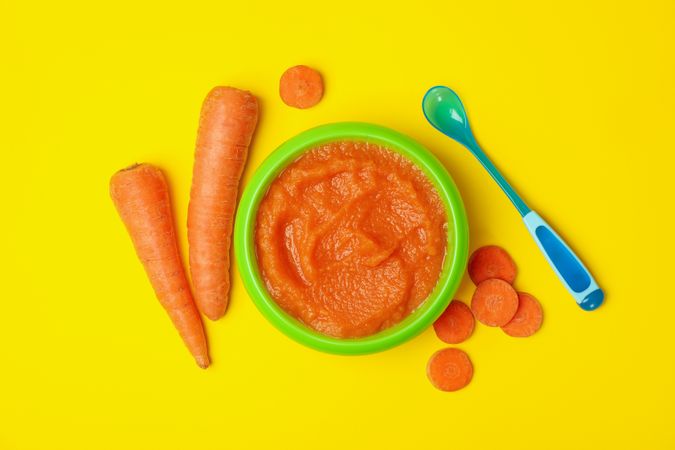 Bowl with vegetable puree on yellow background. Baby food