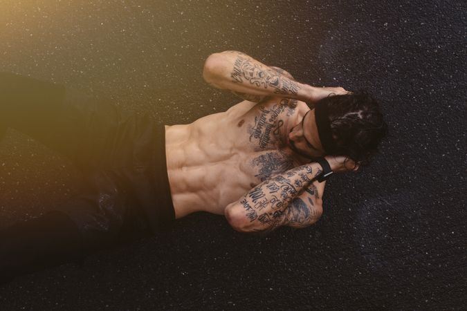 Muscular man doing sit ups on a wet road