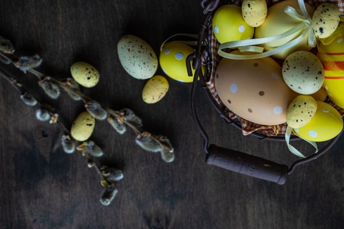 Top view of eggs in basket and pussy willow branches on wooden table