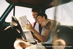 Young couple smiling while planning road trip destination 4AWK80