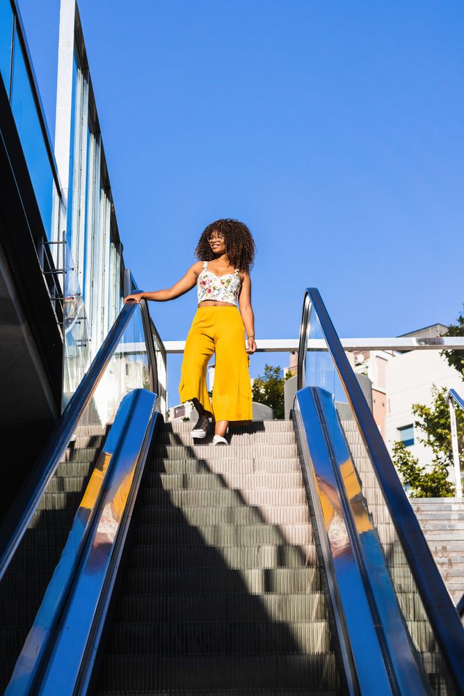 Stylish Black woman on moving stairs