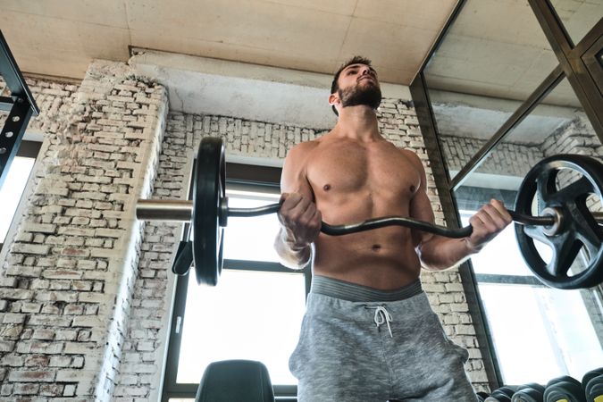 Bearded man exercising with barbell in gym